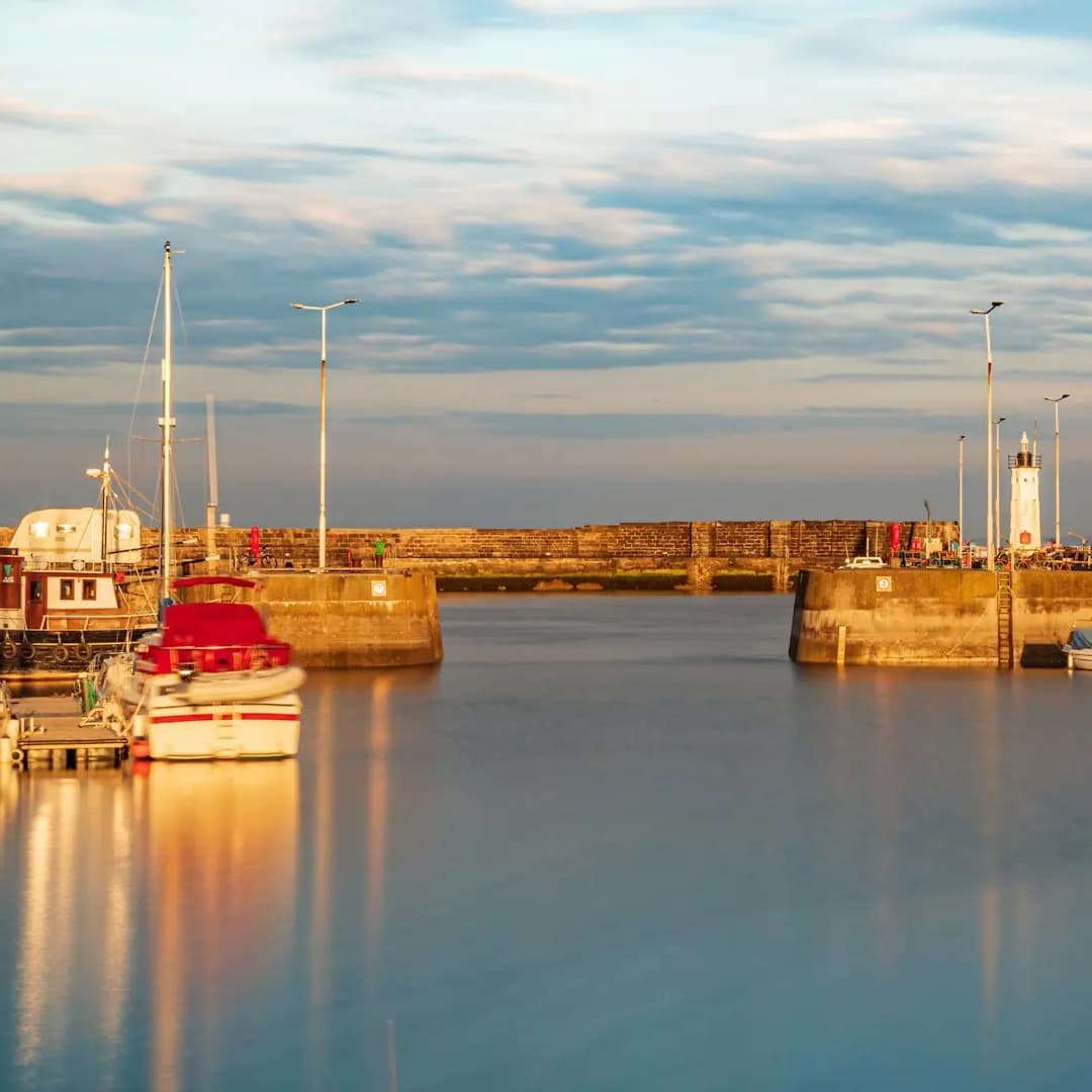 A tranquil harbour at sunrise with golden light reflecting on still water