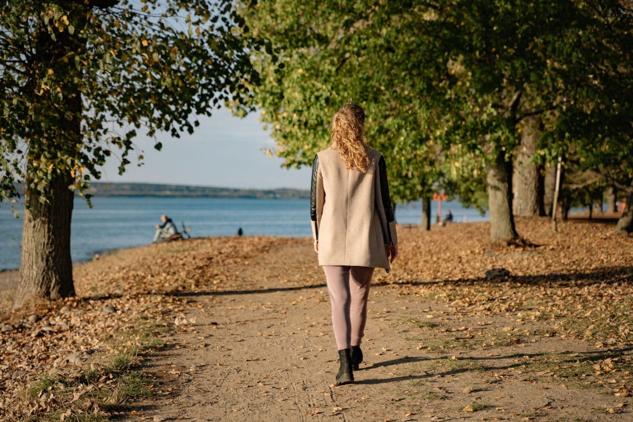 Woman walking free along lakeside path in sunshine