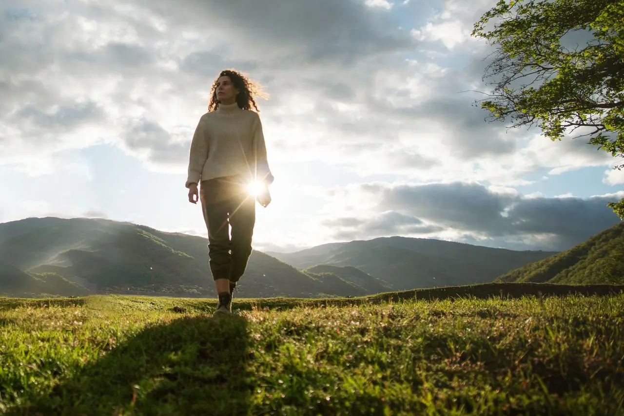 Woman walking in hillside meadow stepping out